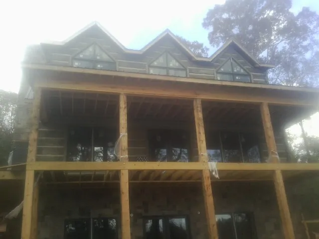 Dormers and porch framing on a large log home under construction — Roof Coating work by our crew in Republic