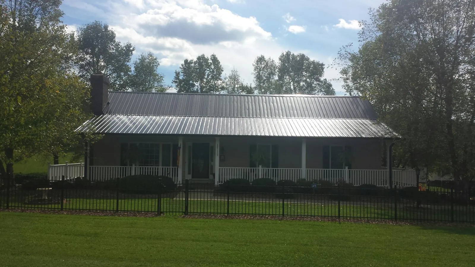 Gray metal roof on a brick ranch with a full width front porch — Gutter Guard Installation work by our crew in Republic