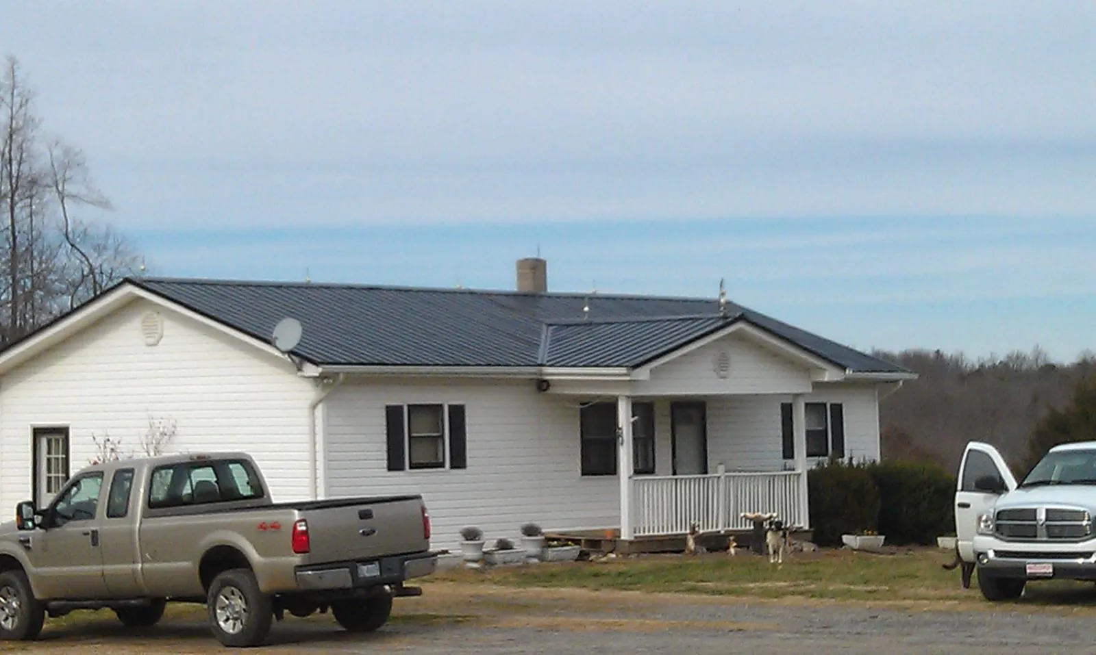 Finished dark metal roof on a white ranch home with work trucks parked in Republic