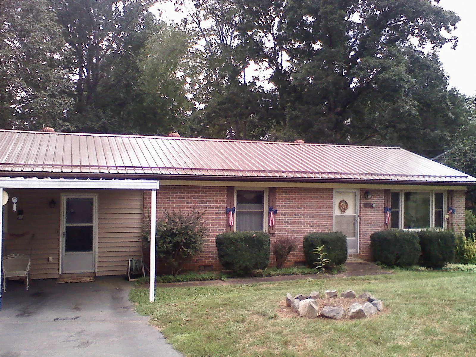 Bronze metal roof and carport on a brick ranch home — Roof Repair work by our crew in Republic